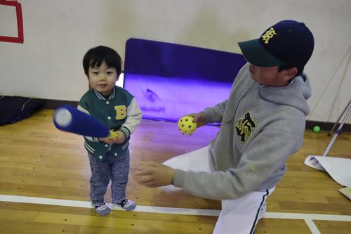 園児の好奇心を探りながら、ボールを使った遊びを一緒に楽しむ野球部の選手